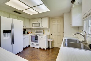 A modern kitchen with white cabinetry, a stainless steel sink, a microwave, an oven, and a refrigerator. - Families w/ Pets Welcome! Retreat 14 Mi to Tampa (Brandon)
