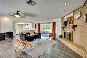 A spacious living room with a dark-colored sofa, a glass coffee table, and a fireplace with a brick wall. - Families w/ Pets Welcome! Retreat 14 Mi to Tampa (Brandon)