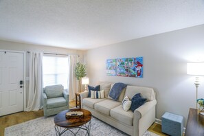 A living room with a beige sofa, a coffee table, a lamp, and a painting on the wall. - Relax at Oxford Retreat! Experience Ole Miss (Oxford)
