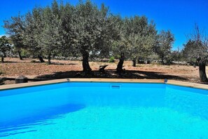 A clear blue swimming pool surrounded by trees.