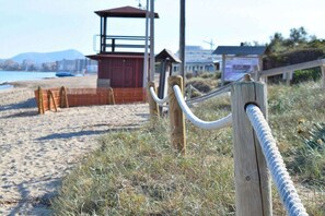 A beach with a lifeguard tower, wooden fence, and a wooden post with a rope.