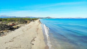 A beach with a clear sky, calm sea, and distant mountains. - Cabin in Llubi with swimming pool (Llubi)