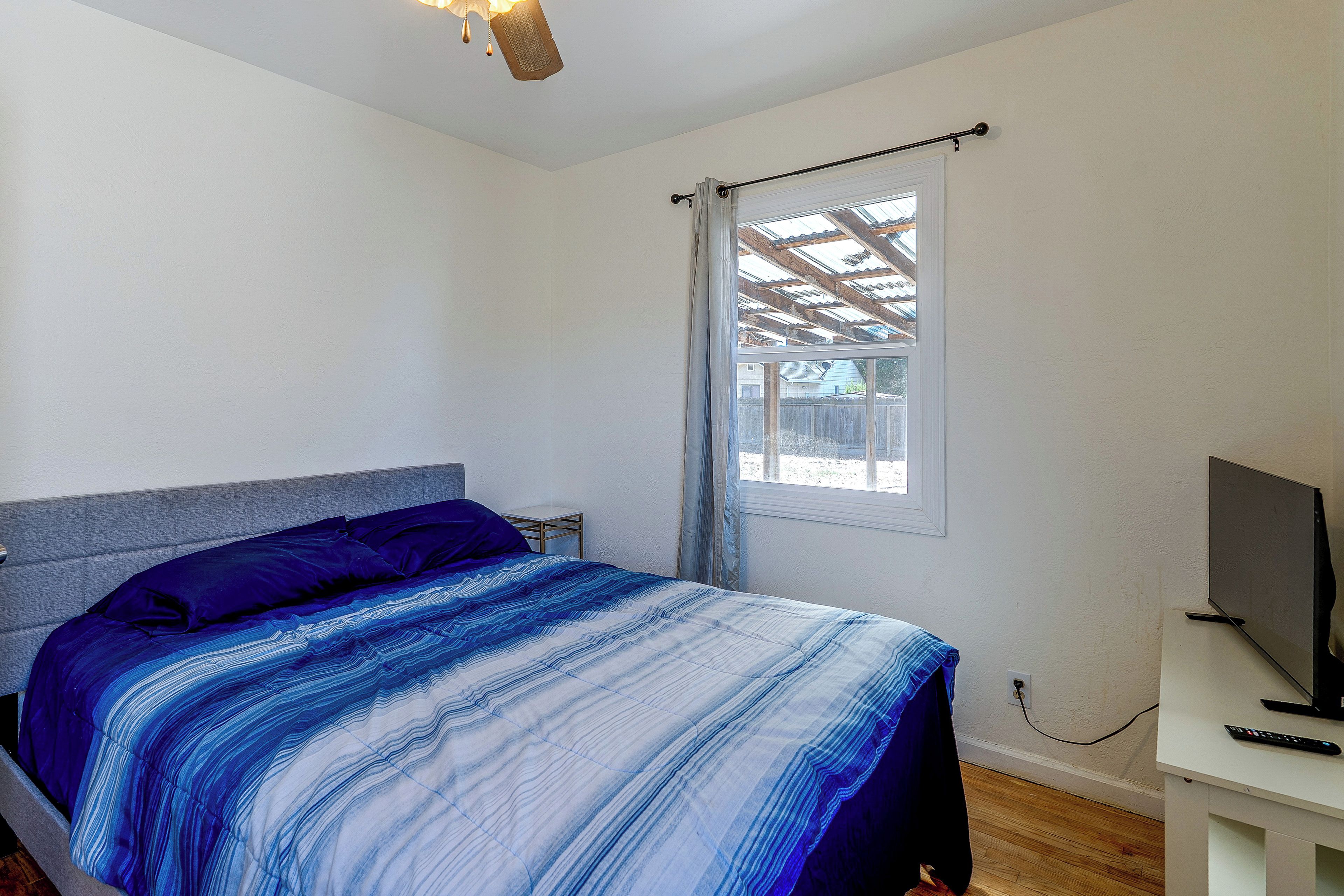 Un dormitorio con cama, televisor y ventana con vistas al exterior.