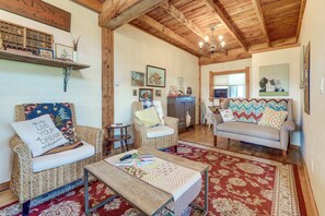 A cozy living room with a wooden ceiling, a sofa, two armchairs, a coffee table, and a rug.