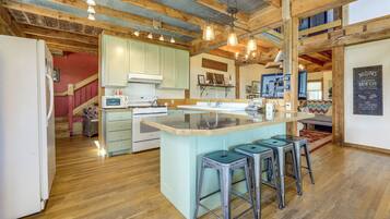 A kitchen with a central island, bar stools, and a microwave.