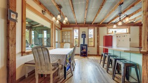 A rustic kitchen with wooden beams, a dining table with chairs, a built-in stove, and a refrigerator.