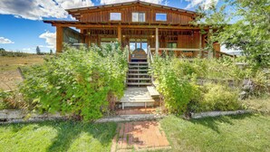 A wooden cabin with a porch, a staircase leading to the entrance, and a clear sky.