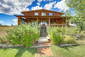 A wooden cabin with a porch, a staircase leading to the entrance, and a clear sky.