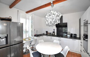 A modern kitchen with a stainless steel refrigerator, a round dining table with chairs, and a unique chandelier. - Stunning home in Espira-de-l'Agly (Espira-de-l'Agly)