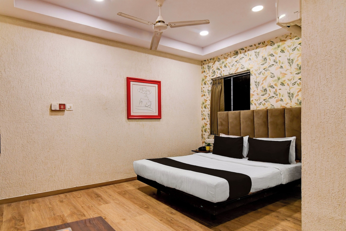 A bedroom with a bed, a ceiling fan, a framed artwork, and a window with curtains.