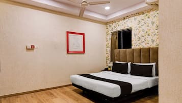 Quarto com cama, ventoinha no teto, uma obra de arte emoldurada e janela com cortinas.