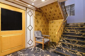 A room with a marble staircase, a chair, and a door with a geometric design. - Townhouse Parkstreet FormerlyHotel Royal (Kolkata)