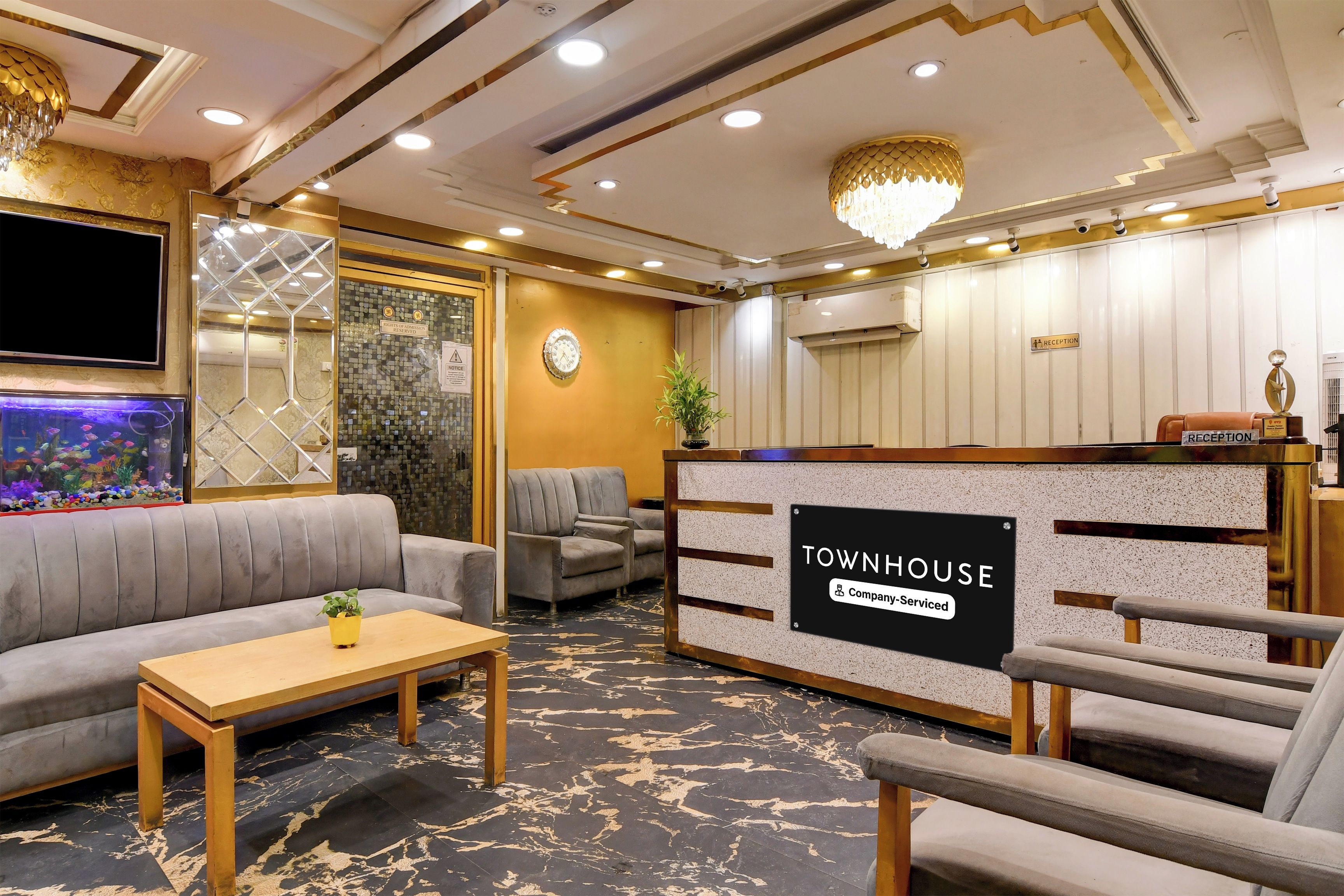 A reception area with a 'Townhouse' sign, a reception desk, seating, a television, and a decorative wall.