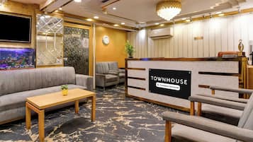 A reception area with a 'Townhouse' sign, a reception desk, seating, a television, and a decorative wall.