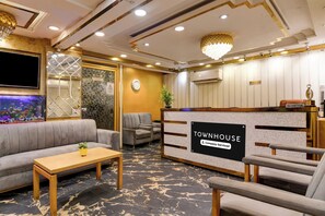 Aula, jossa on kyltti, jossa lukee ”Townhouse”, vastaanottotiski, istuimia, televisio ja koristeellinen seinä.