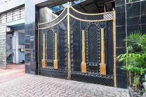 A gated entrance with a decorative metal gate and a potted plant beside it. - Townhouse Parkstreet FormerlyHotel Royal (Kolkata)