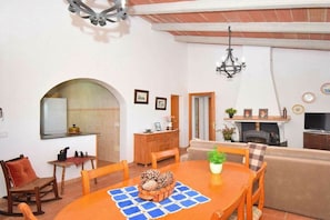 A dining area with a wooden table, chairs, and a chandelier. - Cabin in Muro with swimming pool (Muro)