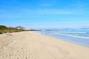 A wide sandy beach with footprints, a clear sky, and distant mountains. - Cabin in Muro with swimming pool (Muro)