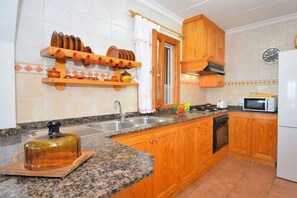 A kitchen with wooden cabinets, a granite countertop, a sink, a stove, and a microwave.