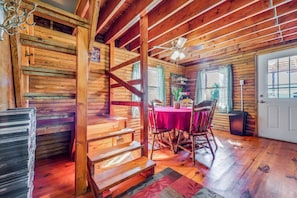 Ein Holzblockhaus-Interieur mit Essbereich, Treppe und einer Tür.