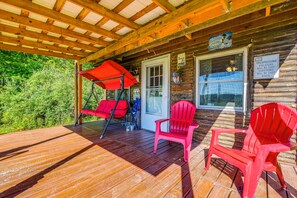 A wooden cabin with a covered porch, red Adirondack chairs, and a sign warning against trespassing. - 100-Acre Milan Cabin w/ Fire Pit & Shared Pond! (Milan)