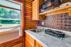 A compact kitchen with a window, a microwave, a sink, and a stove. - 100-Acre Milan Cabin w/ Fire Pit & Shared Pond! (Milan)