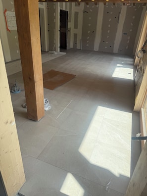 A room under construction with exposed wooden beams, a tiled floor, and construction materials scattered around. - Le Flocon de Neige votre parenthèse à la montagne (Les Avanchers-Valmorel)