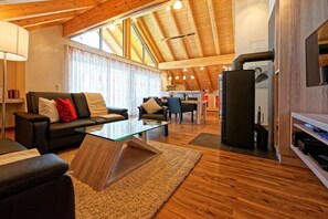 Ein modernes Wohnzimmer mit einem Glastisch, Ledersofas und einer Holzbalkendecke.