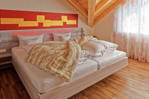 Ein Schlafzimmer mit einem Bett, Kissen, einer Decke, einem hölzernen Kopfteil und einer roten Wanddekoration.