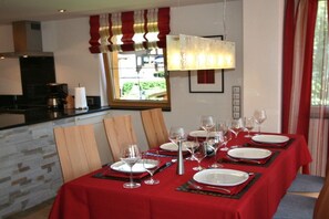 A dining area with a red tablecloth, white plates, and wine glasses set for a meal. - Alpenflair holiday apartment 310 (Oberstdorf)