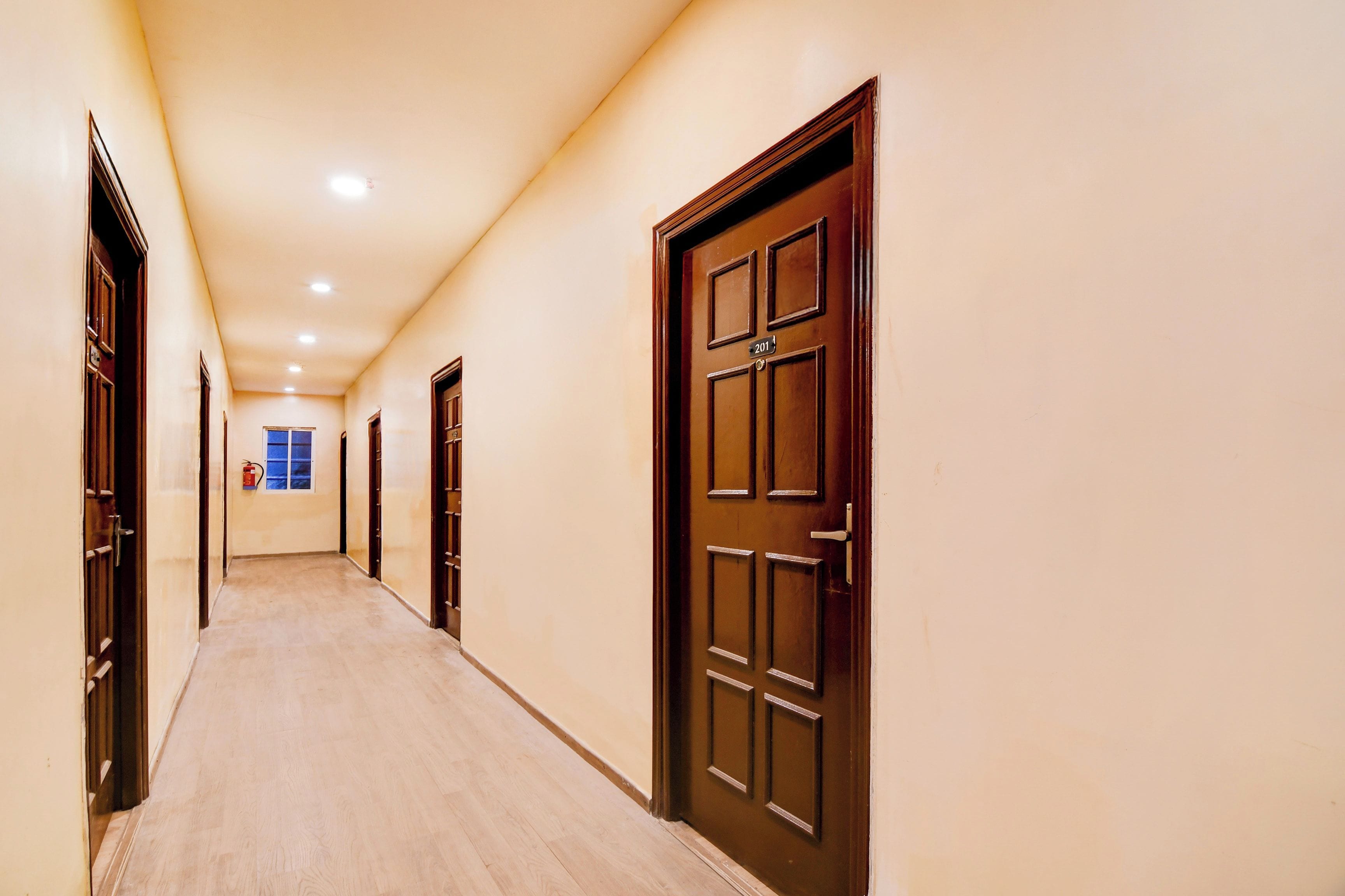 A corridor with wooden doors and a fire extinguisher on the wall.