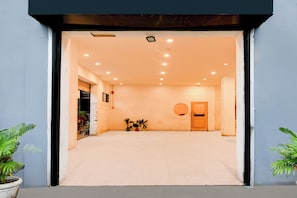 Un espacio interior con suelo de baldosas, una puerta y plantas en macetas.