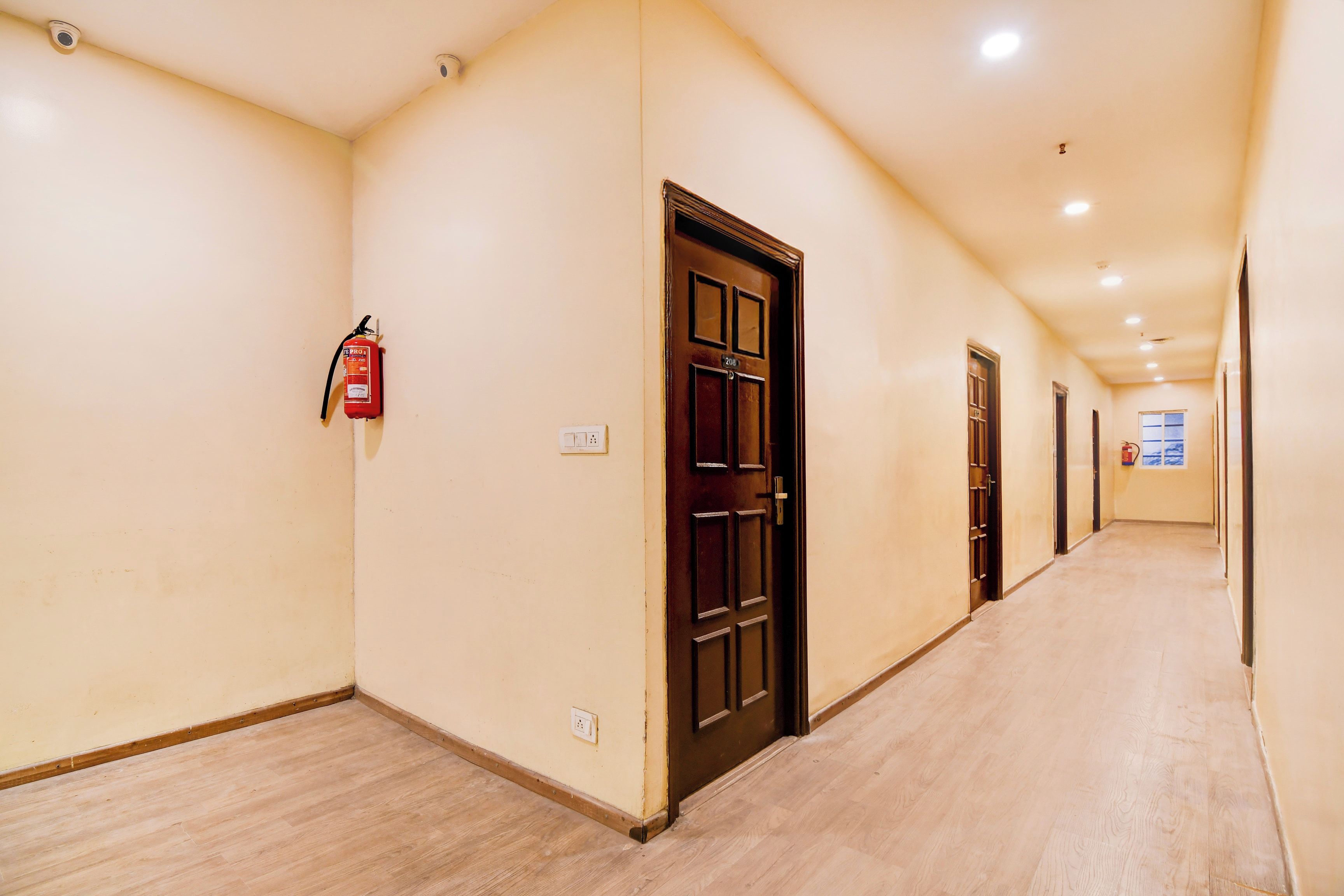 A corridor with doors, a fire extinguisher, and a light switch on the wall.