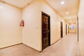 A corridor with doors, a fire extinguisher, and a light switch on the wall.