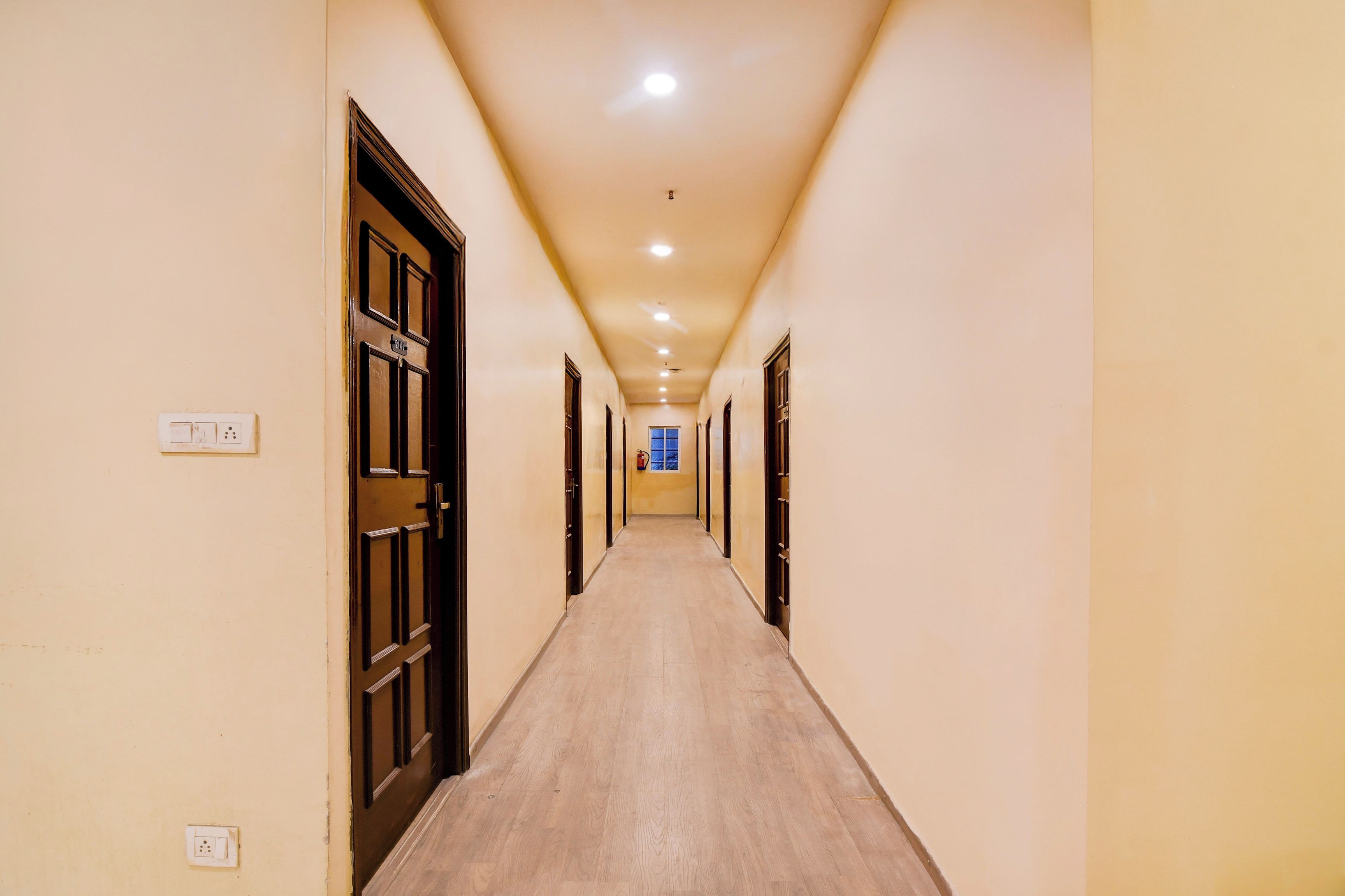 A long, narrow hallway with doors on both sides, leading to individual rooms.