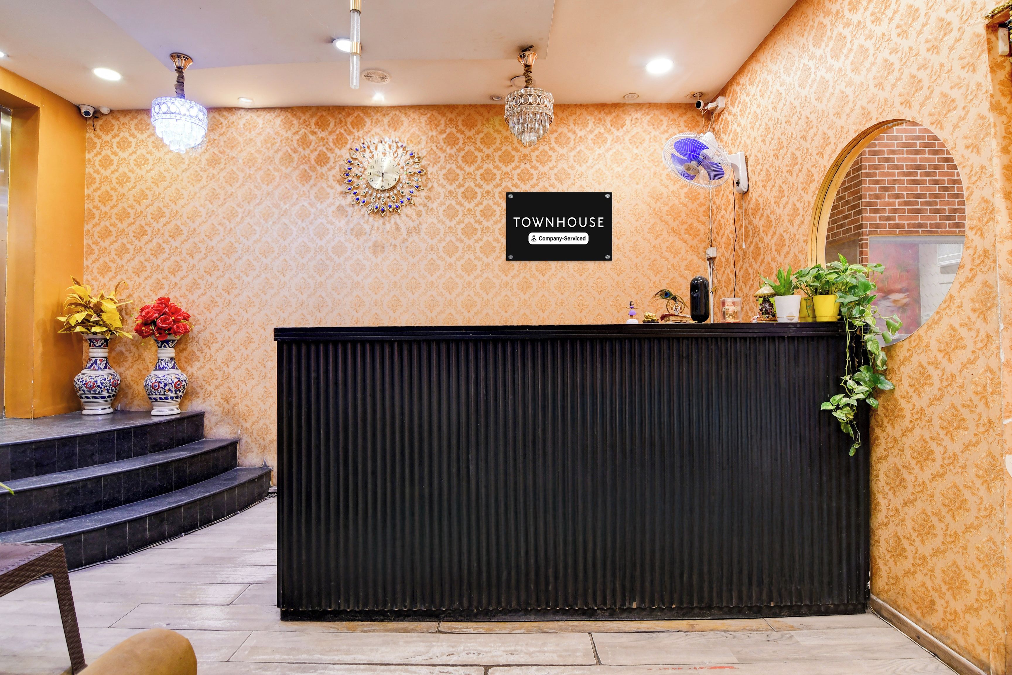 A reception area with a black reception desk, a clock, and a sign indicating it's a company-serviced townhouse.