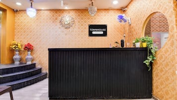 Ett entréområde med en svart receptionsdisk, en klocka och en skylt som visar att det är ett radhus som sköts av företaget.