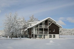A two-story building with a balcony, surrounded by snow-covered trees. - House Seewiese No. 1 (Titisee-Neustadt)