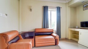 Una sala de estar con dos sofás de cuero, un televisor y un ventanal con cortinas.