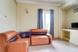 Ein Wohnzimmer mit zwei Ledersofas, einem Fernseher und einem Fenster mit Vorhängen.
