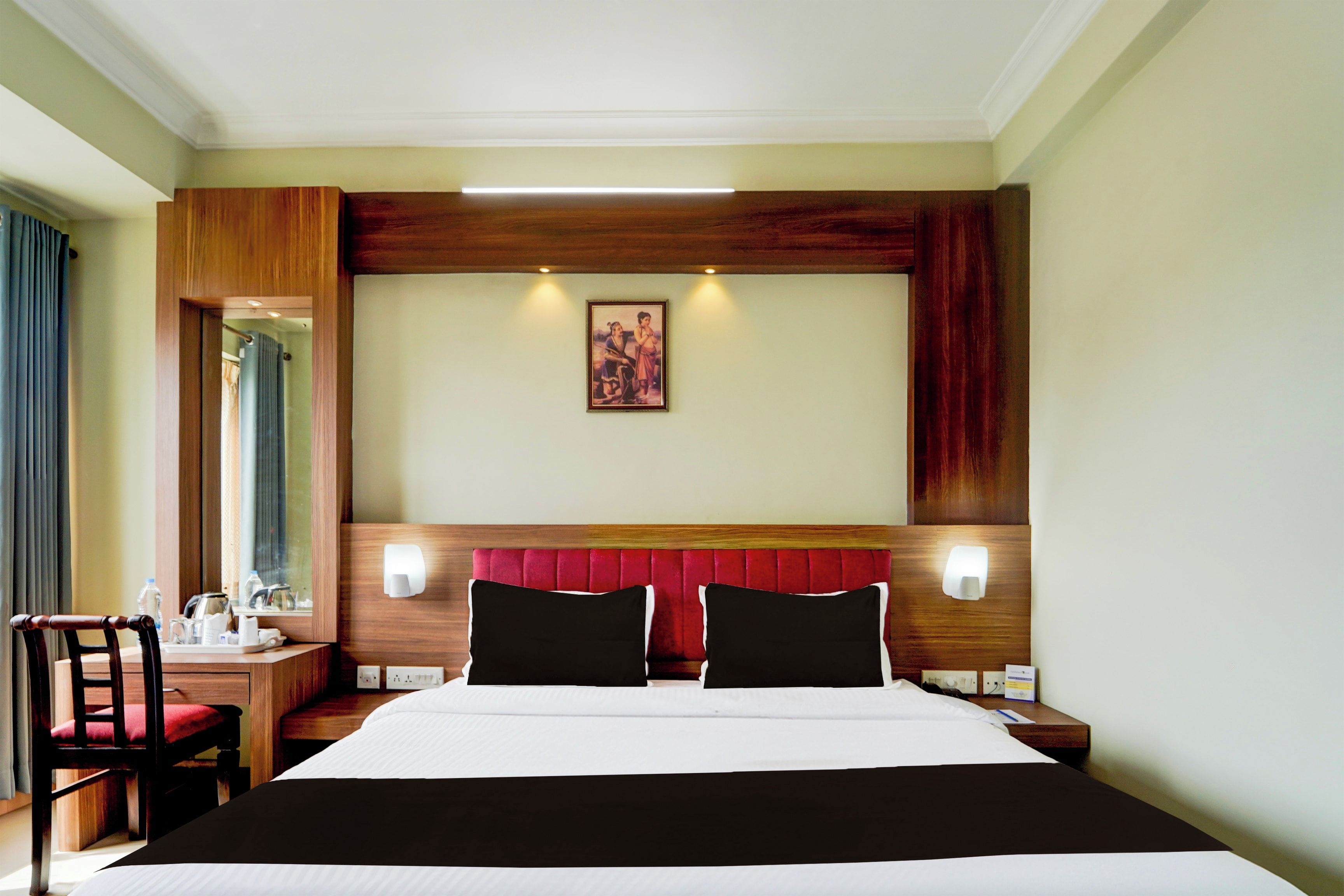 Habitación de hotel con una cama grande, un escritorio con una silla, un espejo y un cuadro en la pared.