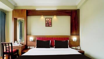Habitación de hotel con una cama grande, un escritorio con una silla, un espejo y un cuadro en la pared.