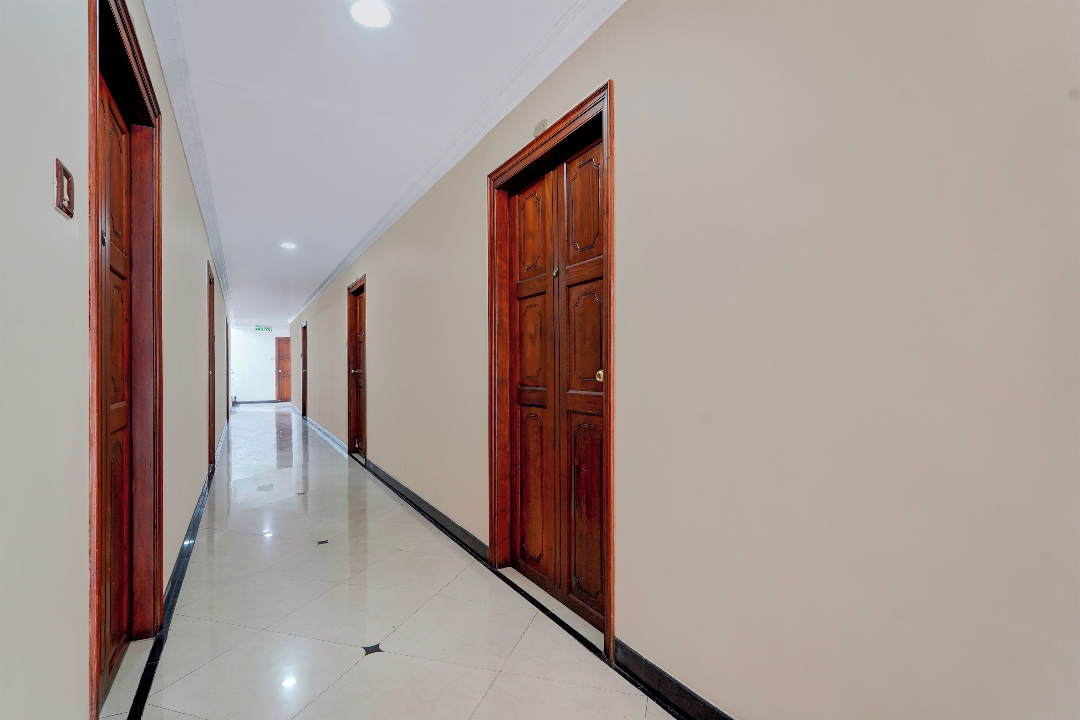 Un pasillo con puertas de madera y suelo de baldosas.