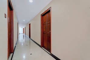 A corridor with wooden doors and a tiled floor.