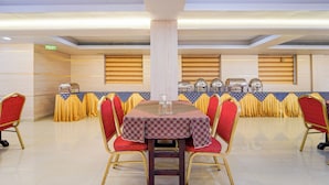 Un comedor con una mesa central, sillas tapizadas en rojo y estaciones de buffet al fondo.