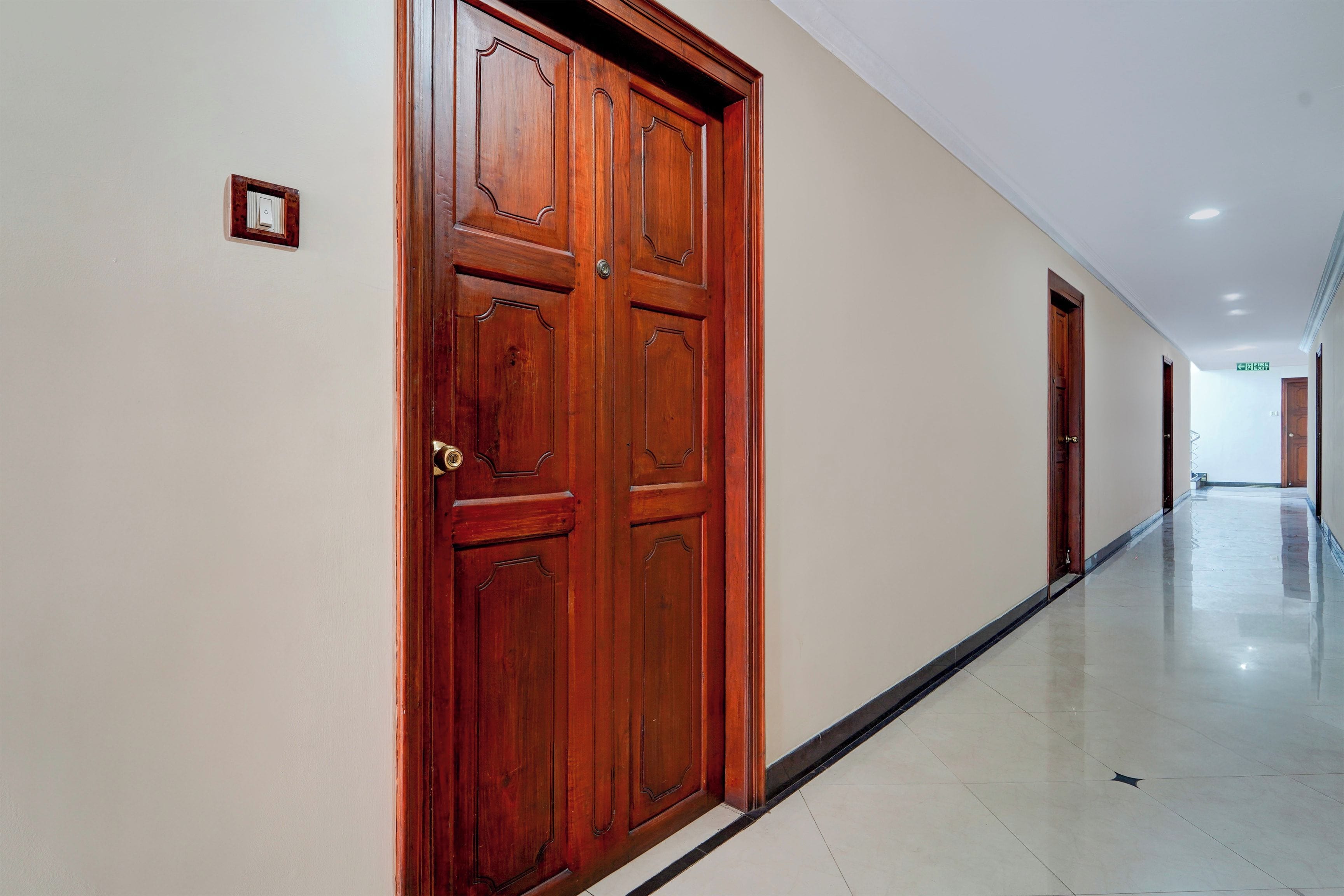 Un pasillo con puertas de madera y suelo de baldosas.