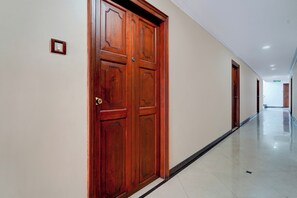 A corridor with wooden doors and a tiled floor.