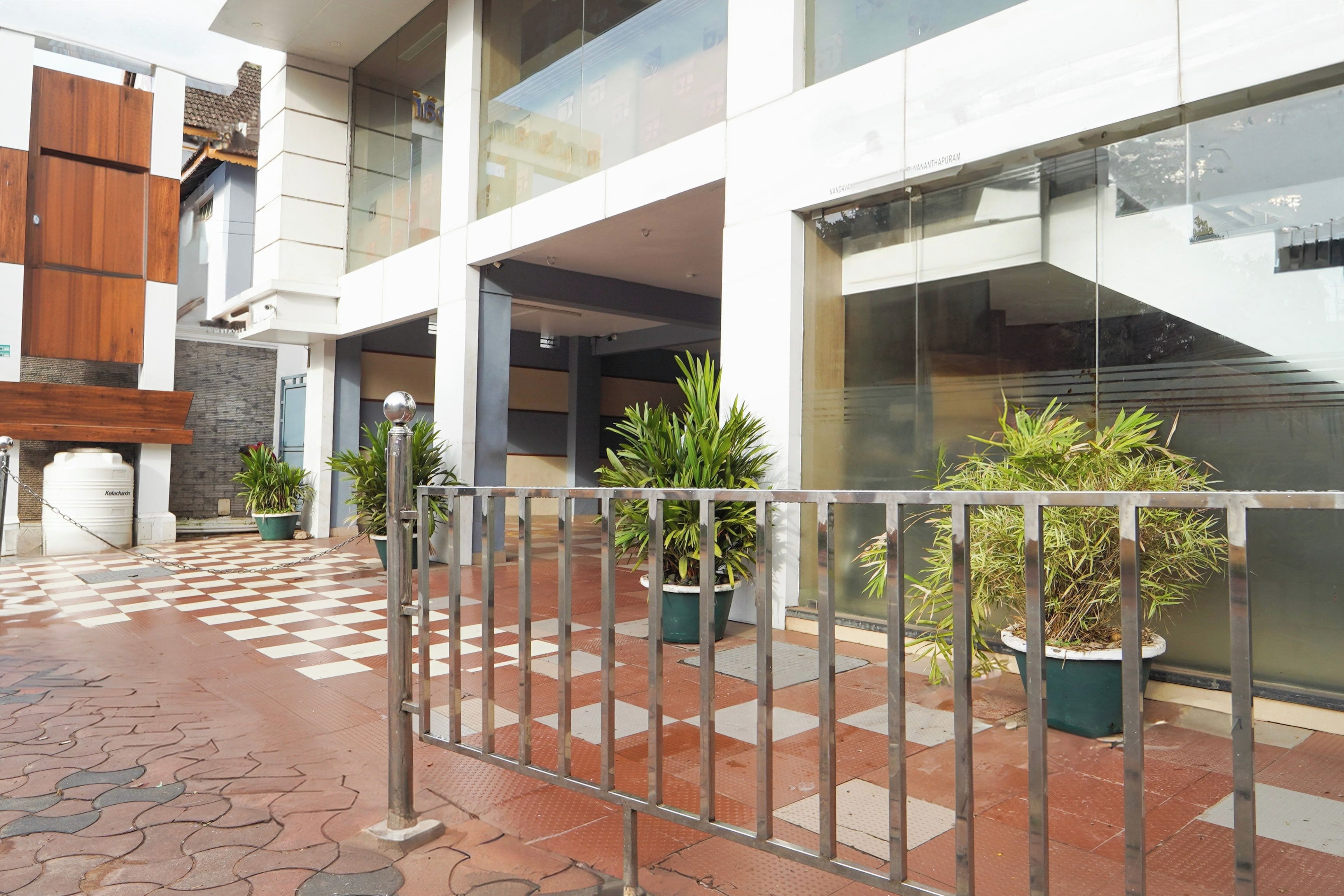 Un edificio moderno con piso a cuadros, plantas en macetas y una cerca metálica.