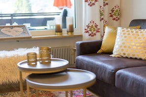 A cozy living room with a leather sofa, a round coffee table, and a small side table. - Alpenflair holiday apartment 227 (Oberstdorf)