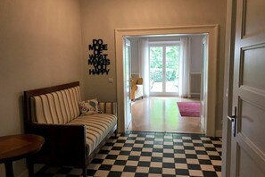 A hallway with a checkered floor, a sofa, and a door leading to a balcony. - Villa Hoyerberg Lake (Lindau)